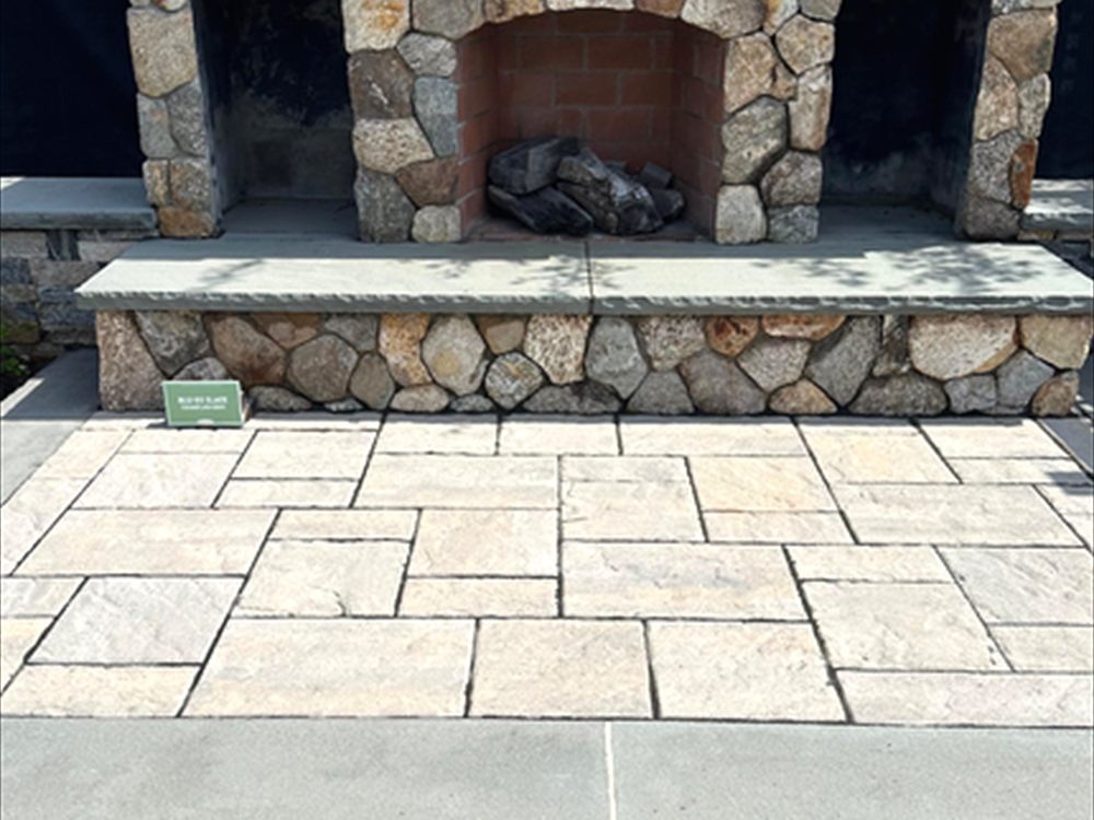 Outdoor stone fireplace with a cut hearth and side benches on a paver patio