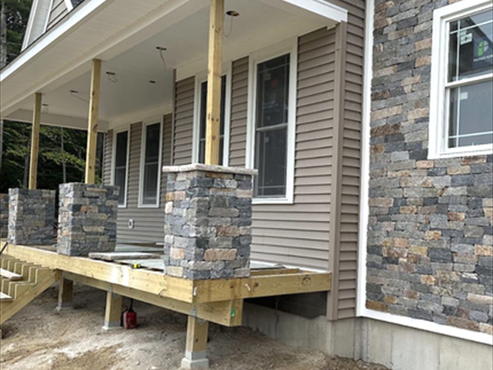 Stone veneer applied to porch columns and the foundation skirt of a house with siding above